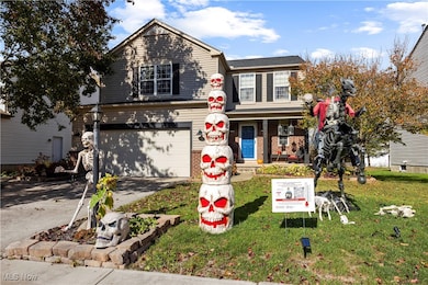 Traditional-style home with a porch, driveway, a garage, and a front yard