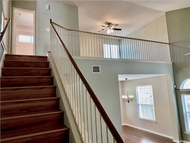 Staircase featuring ceiling fan, a chandelier, wo