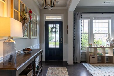 Entryway featuring dark wood-type flooring, crown molding, and wainscoting