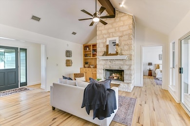 Living area with beamed ceiling, light wood finished floors, ceiling fan, high vaulted ceiling, and a fireplace