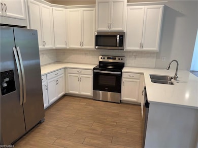 Kitchen with stainless steel appliances, a sink, light wood-style flooring, and tasteful backsplash