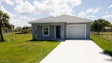 Ranch-style house featuring driveway, stucco siding, fence, a front lawn, and a garage