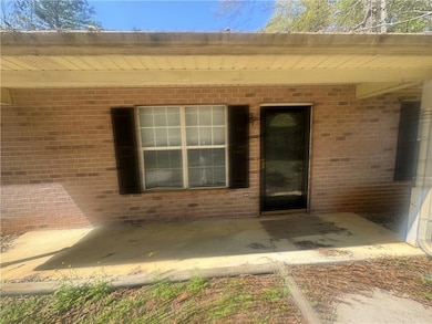 Entrance to property featuring brick siding and a patio