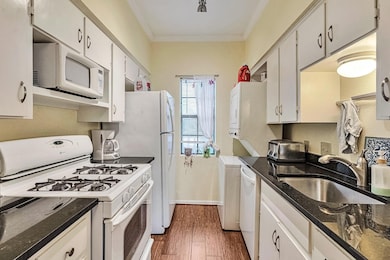 Kitchen with white appliances, crown molding, dar