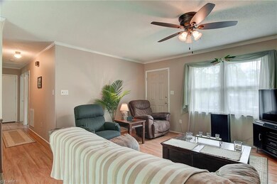 From the side entry door, the living room sits to the right.  The living room features a ceiling fan, crown moulding, two large windows overlooking the front yard, and laminate wood flooring.