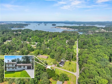 Aerial view of property and surrounding area featuring a heavily wooded area, a large body of water, and property parcel outlined