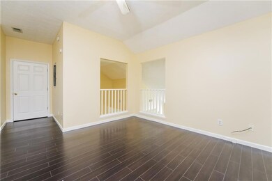 Empty room with dark wood-style flooring, baseboards, and vaulted ceiling