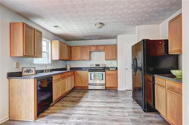 Kitchen with black appliances, a sink, light wood-