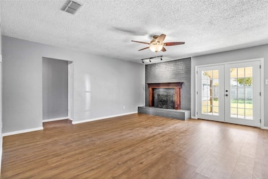 Unfurnished living room featuring wood finished floors, a fireplace, ceiling fan, a textured ceiling, and track lighting