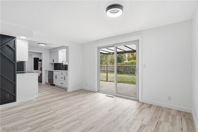 Unfurnished living room featuring light wood-type flooring and baseboards