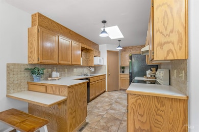 Kitchen featuring white microwave, range, a peninsula, and tasteful backsplash