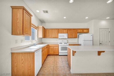 Kitchen with white appliances, a kitchen bar, ligh