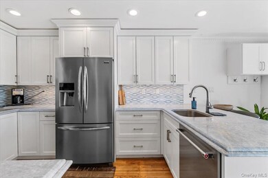 Kitchen featuring appliances with stainless steel finishes, white cabinetry, backsplash, a peninsula, and recessed lighting