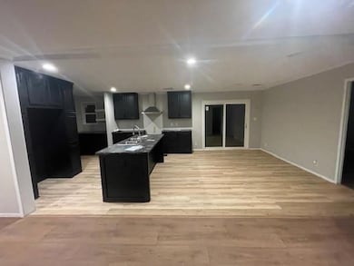 Kitchen with wall chimney exhaust hood, sink, and 