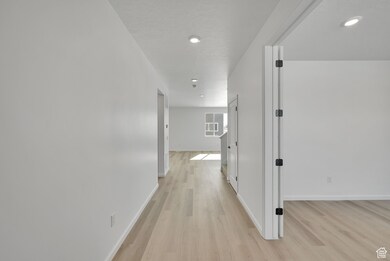Corridor featuring light wood-type flooring, baseboards, and recessed lighting