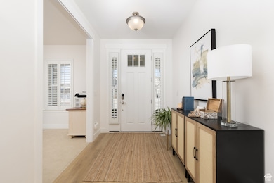 Foyer featuring light wood-style flooring, baseboards, and light carpet