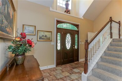 The entry of this massive home (4346 SF), boasts a stained wood door w/ a curved transom window above, and side windows. There is an art niche above the entry, space seen to the left in the photo for a large piece, and the staircase leading upstairs.