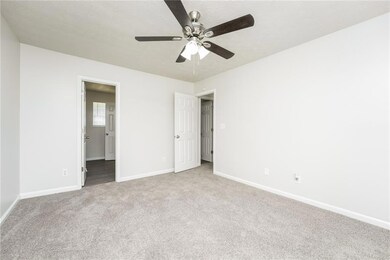 Unfurnished bedroom with carpet floors, ensuite bathroom, and a ceiling fan