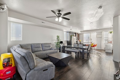 Living area featuring a textured ceiling, wood finished floors, and ceiling fan