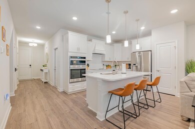 Kitchen featuring appliances with stainless steel finishes, light wood finished floors, a breakfast bar area, light countertops, and recessed lighting