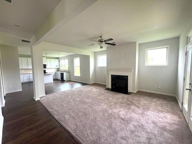 Unfurnished living room featuring ceiling fan, baseboards, a fireplace with flush hearth, and dark wood finished floors