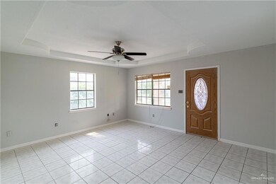 Entryway featuring light tile flooring, ceiling fan, and a raised ceiling