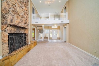 Unfurnished living room featuring carpet, baseboards, stairs, a fireplace, and a towering ceiling