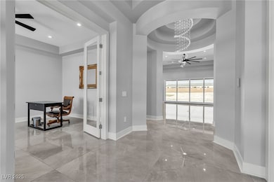 Hallway featuring a raised ceiling, a chandelier,