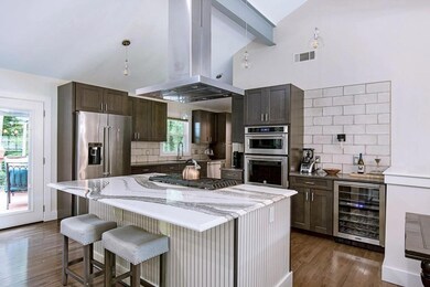 Kitchen with backsplash, appliances with stainless steel finishes, beverage cooler, and island range hood