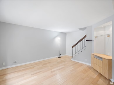 Unfurnished room with light wood-style floors, stairway, and recessed lighting