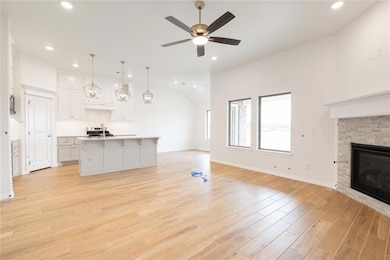 Kitchen featuring stainless steel gas range oven, black microwave, exhaust hood, light wood-style flooring, and backsplash