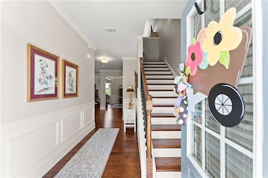 Staircase with crown molding, wood finished floors