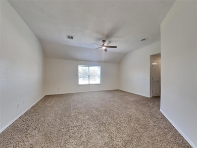 Carpeted spare room with a ceiling fan, vaulted ceiling, and baseboards