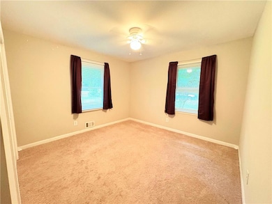 Carpeted empty room with healthy amount of natural light, baseboards, and a ceiling fan