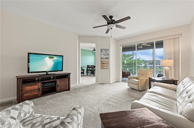 Carpeted living room with ceiling fan and baseboar