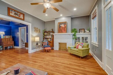 Living area featuring baseboards, light wood finished floors, a textured ceiling, a ceiling fan, and stairs