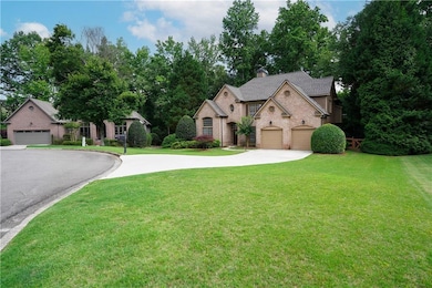 View of front of property with asphalt driveway, brick siding, a front yard, a chimney, and a garage
