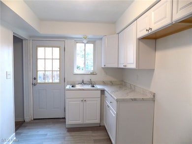 Kitchen featuring white cabinetry, light countertops, and LVT flooring
