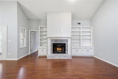 Unfurnished living room featuring dark wood-type flooring, a brick fireplace, and a textured ceiling