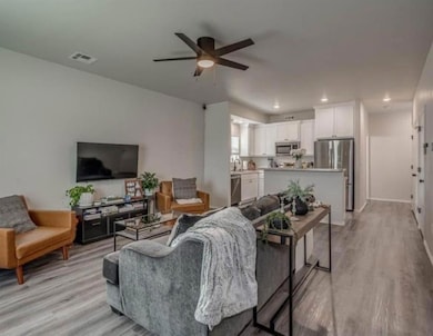 Living room featuring a ceiling fan, light wood-st