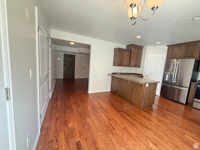 Kitchen with appliances with stainless steel finishes, dark wood finished floors, a breakfast bar, a peninsula, and a textured ceiling