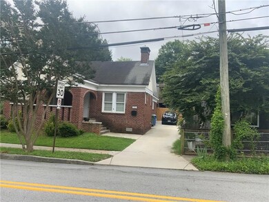 View of front facade with crawl space, concrete driveway, brick siding, and a chimney