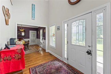 Foyer entrance with plenty of natural light, wood finished floors, a wainscoted wall, and a towering ceiling