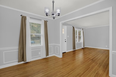 Empty room with crown molding, light wood finished floors, and a chandelier