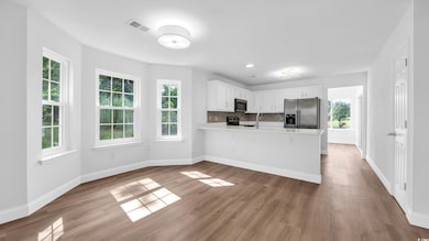 Kitchen featuring stainless steel appliances, light countertops, a peninsula, wood finished floors, and white cabinets