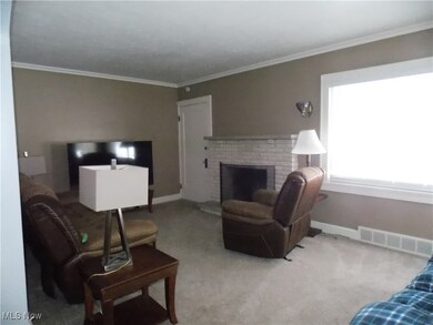 Living room featuring carpet, a brick fireplace, and crown molding