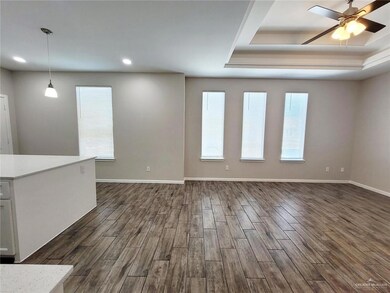 Unfurnished living room with dark wood-style flooring, plenty of natural light, a ceiling fan, a raised ceiling, and recessed lighting