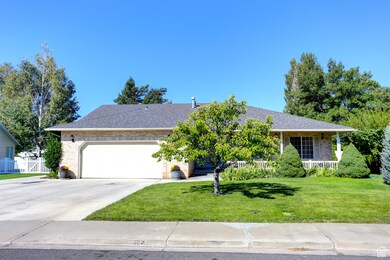 Ranch-style house with driveway, a garage, covered porch, brick siding, and roof with shingles