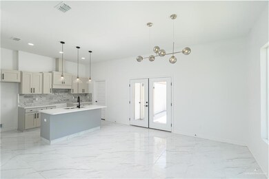 Kitchen featuring light tile patterned flooring, tasteful backsplash, pendant lighting, and an island with sink