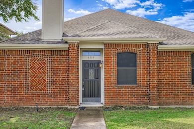 Entrance to property with a shingled roof, brick siding, and a yard